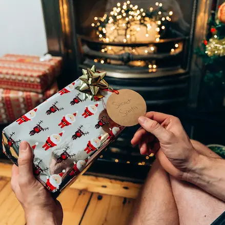 En person rækker en julegave frem, hvilket illustrerer UNICEF’s juleindsamlinger og muligheden for at give støtte til børn i nød i højtiden